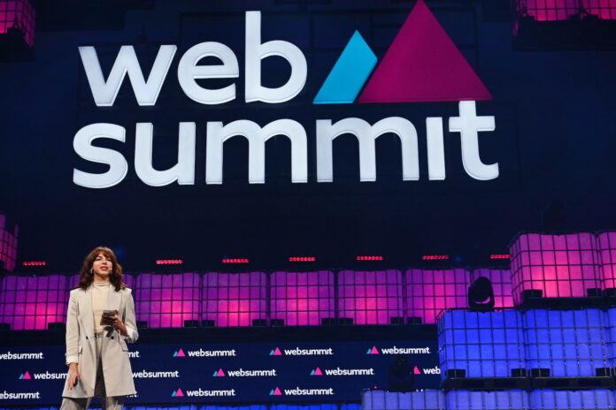 A woman stands on stage in front of a Web Summit sign