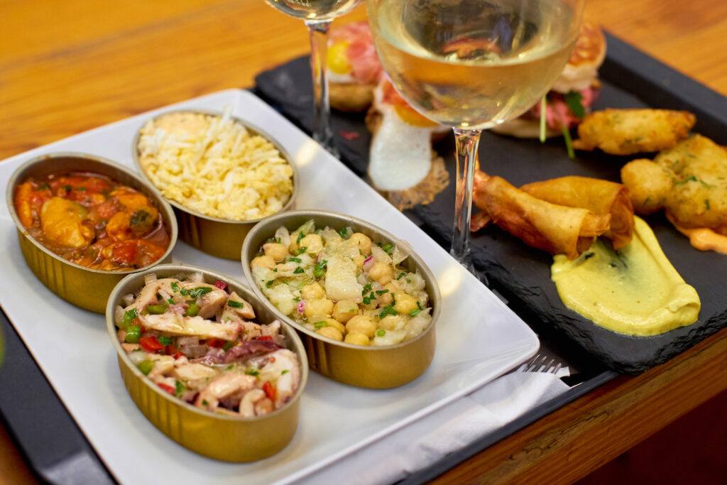 A set of traditional portuguese snacks with codfish, mussels, octopus with a glass of vinho verde