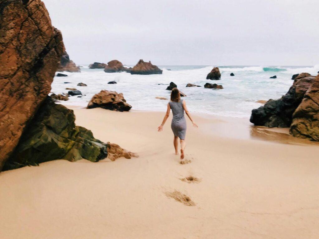 A young child runs along a rocky Algarve beach