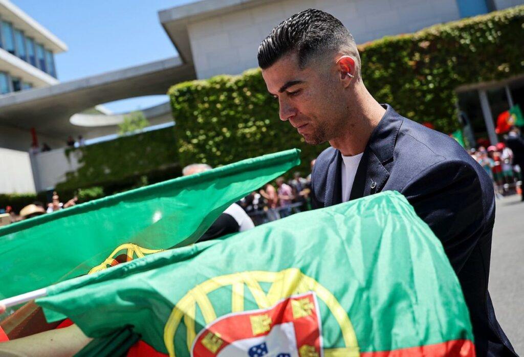 Cristiano Ronaldo stands in between Portuguese football flags