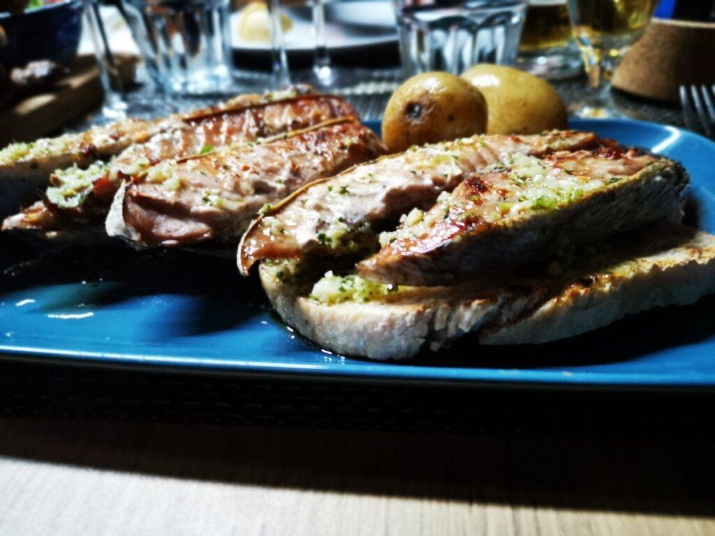 Tuna steaks seen on bread placed on a blue plate.