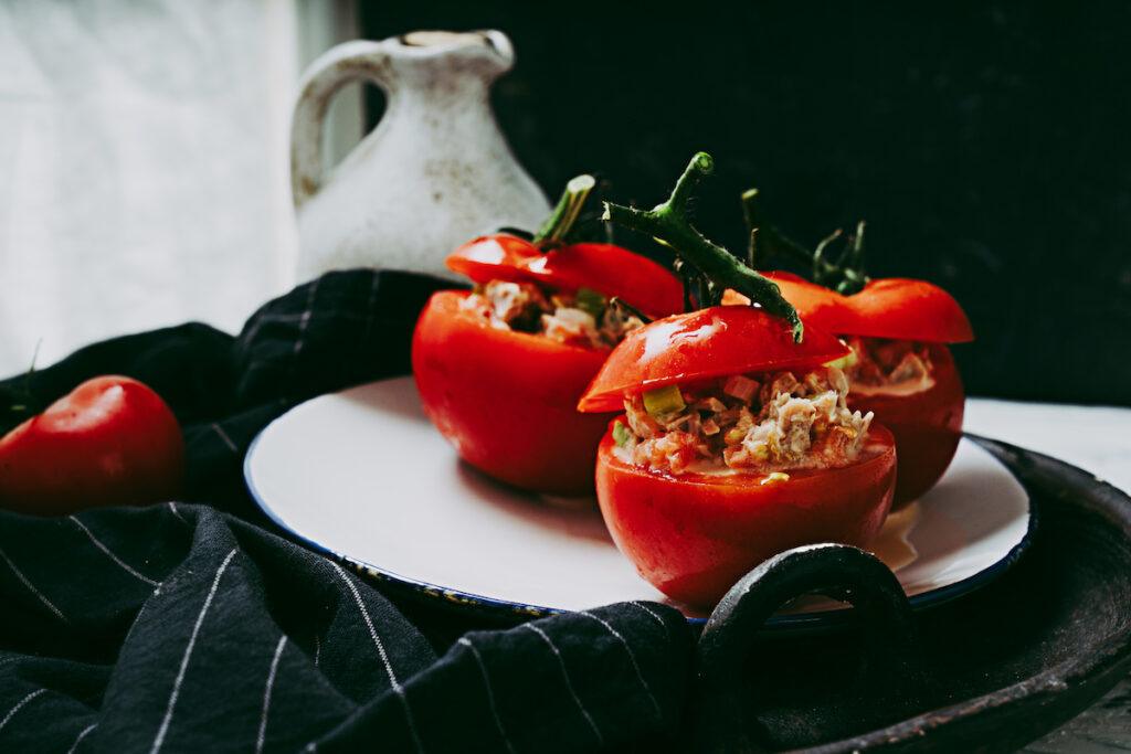 Traditional portuguese snack tomatoes stuffed with canned tuna salad over the white table cloth, decorated with napkin.