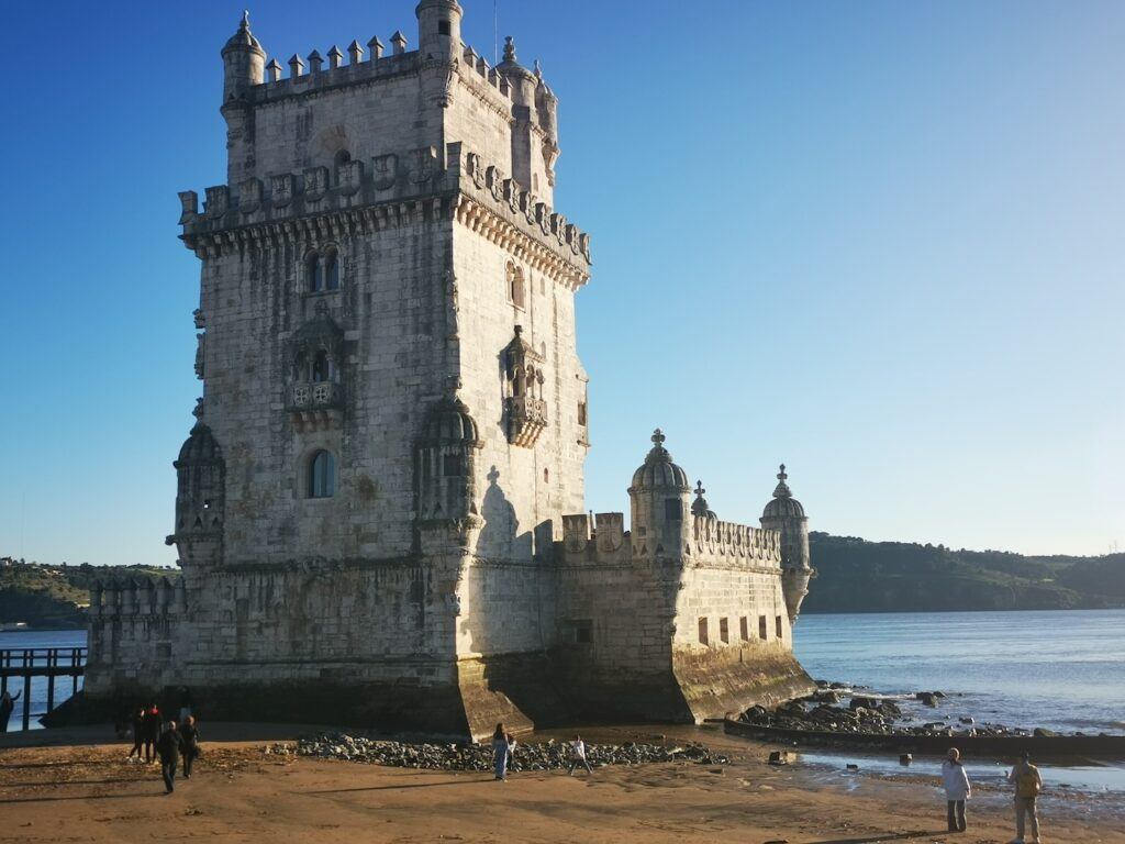 The Tower of Belem, seen from the bank with the Tagus river in the background.