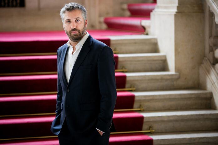 Pedro Nuno Santos standing in front of stairs with a red carpet.