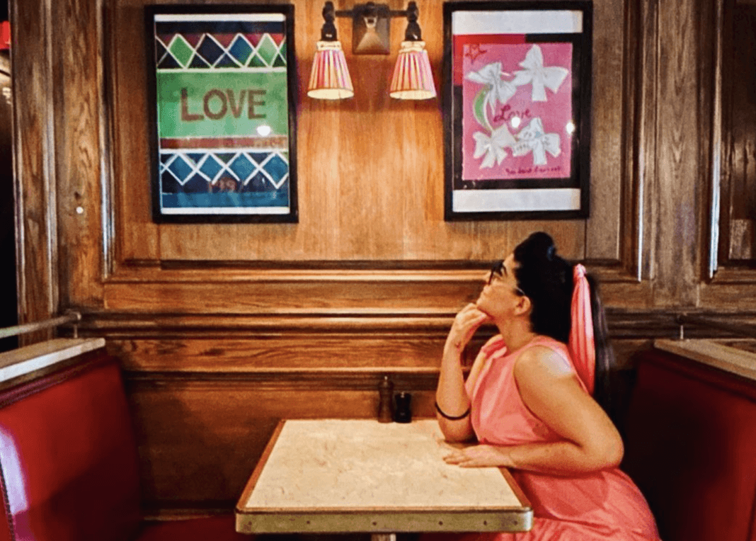 Filipa Gomes sits at a table in a diner style restaurant and looks up at wall posters