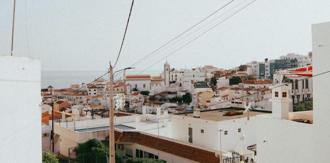 A narrow street in Albufeira, Portugal with white house and a light blue sky