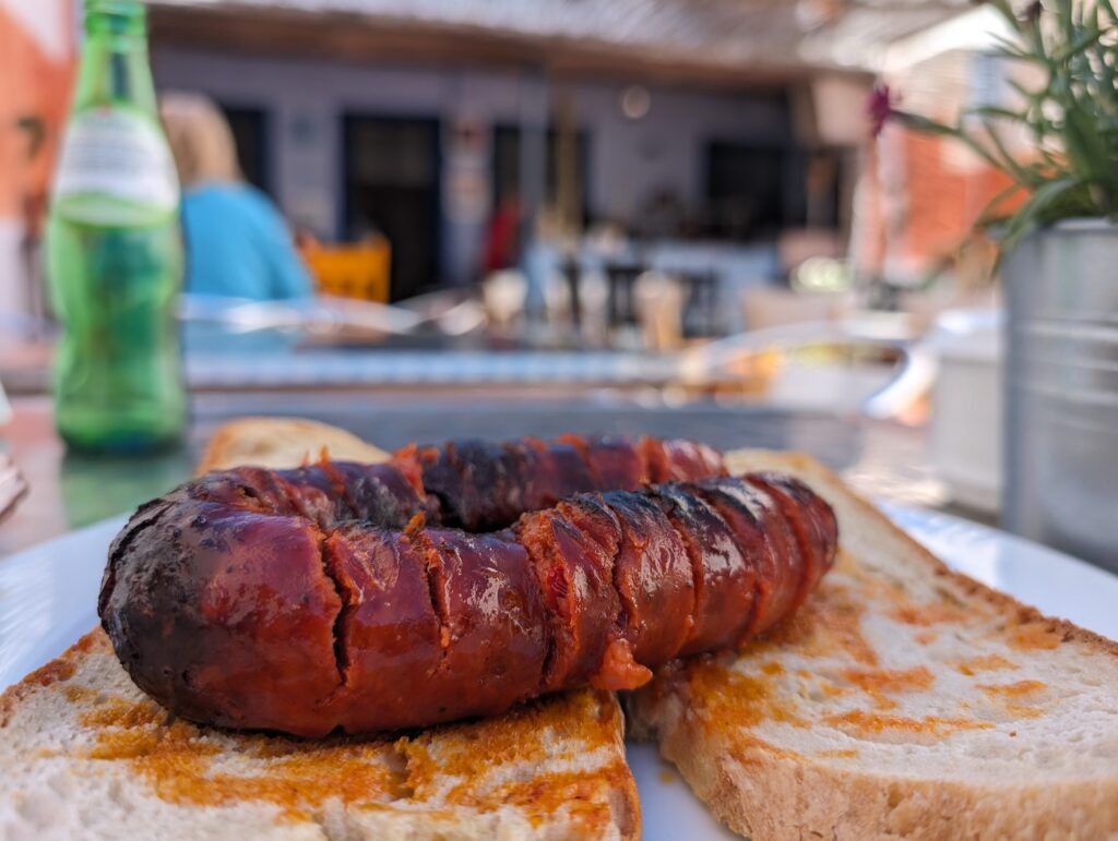 Grilled chorizo on two pieces of bread served at a restaurant table