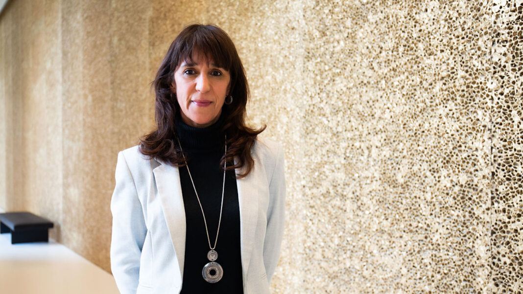 Helena Carreiras in formal attire with a stone wall background.