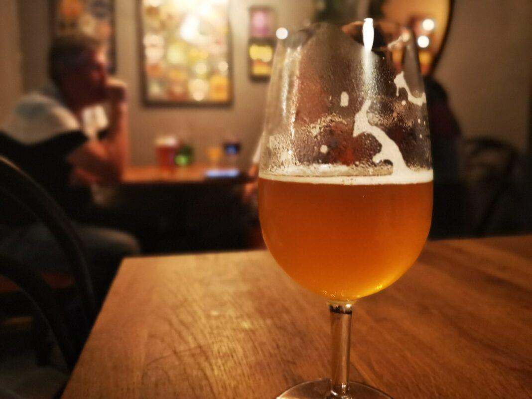 A beer glass which is half empty on a bar counter