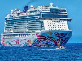 A large , white and colourful cruise ship at sea