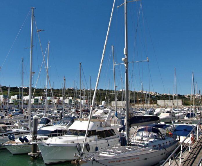 Boats moored in a marina in Albufeira, Portugal with a clear blue sky.