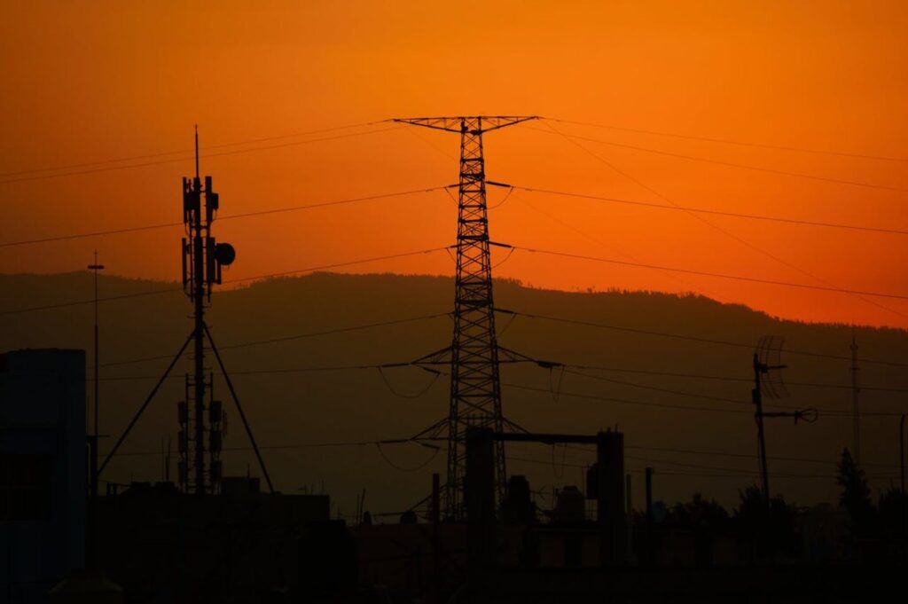 A sunset in Portugal with an electricity pylon and mobile phone antenna in the background.