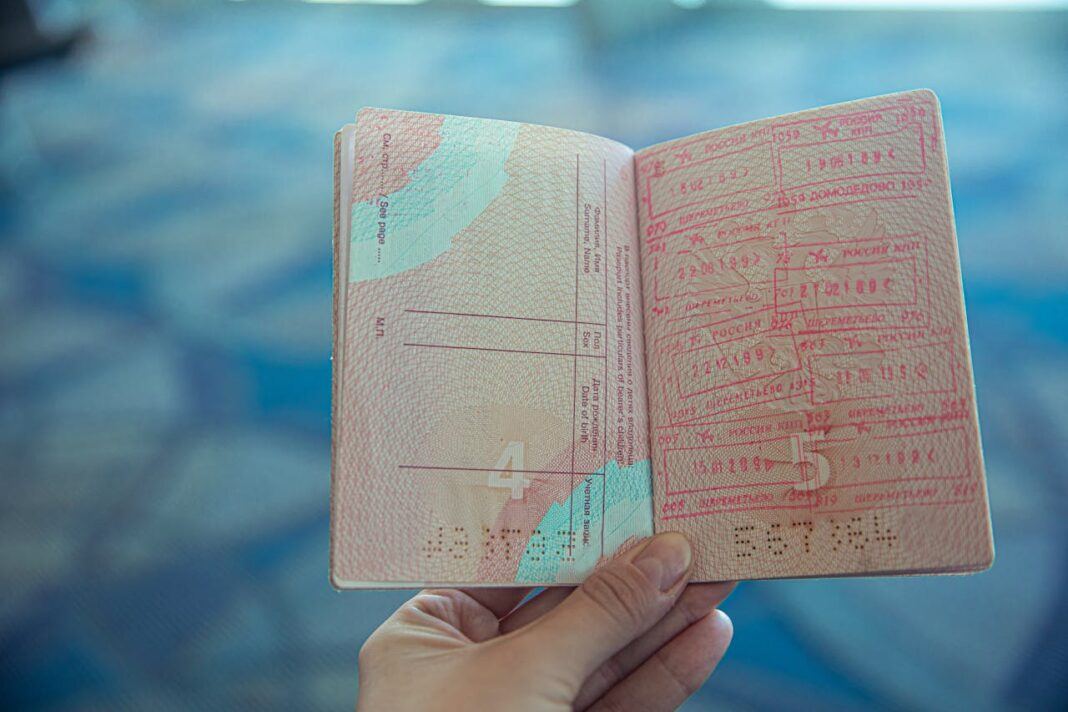 A passport is held open showing visa stamps on the right hand page