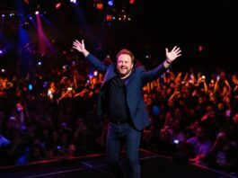 Ricky Gervais performing live in a packed venue.