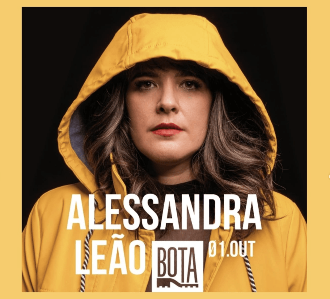 Alessandra Leão wears a yellow jacket with the hood pulled up and text detailing a concert of hers is displayed beneath her face in white text.