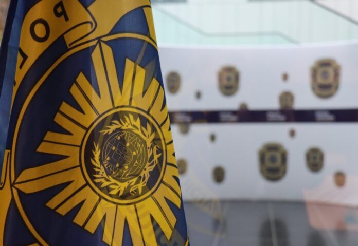 The flag of the Judicial Police of Portugal, with hoarding in teh background also showing the police forces logo.