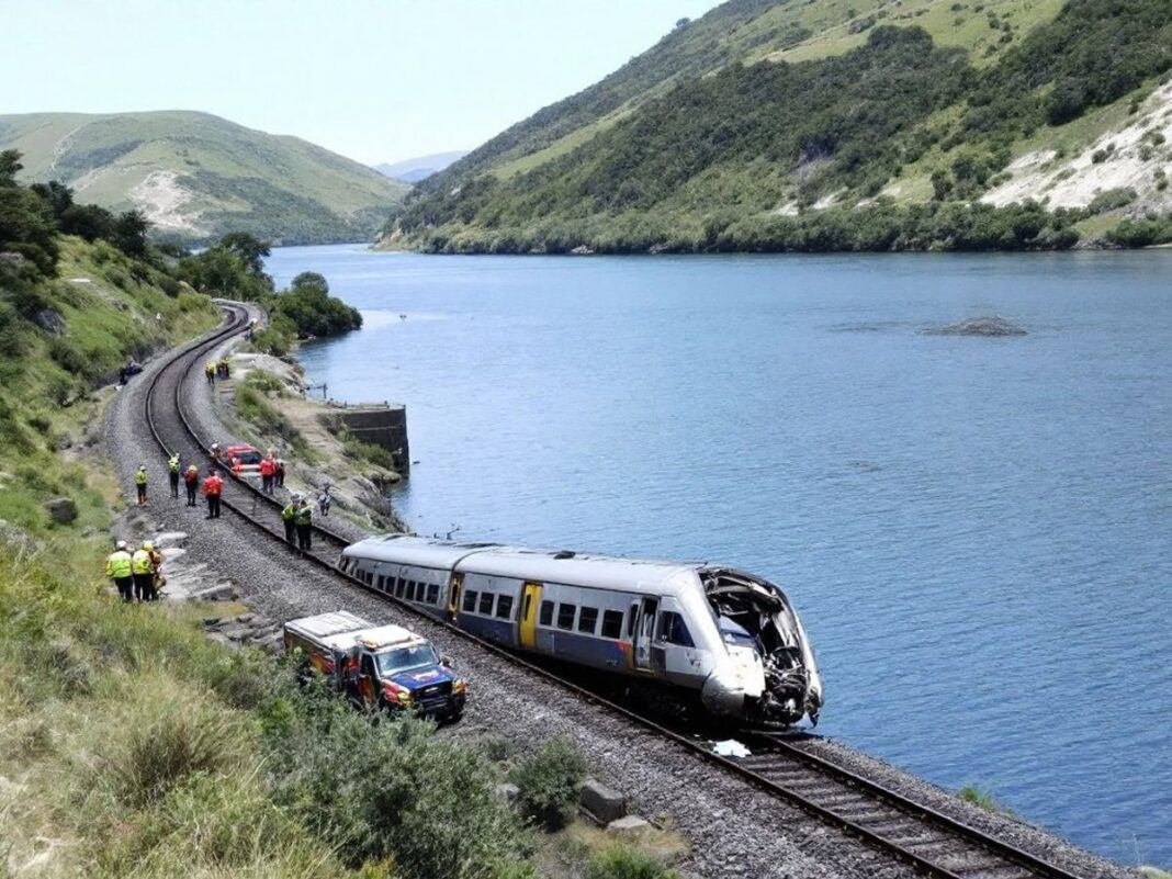 Derailed train near Douro River with green hills.