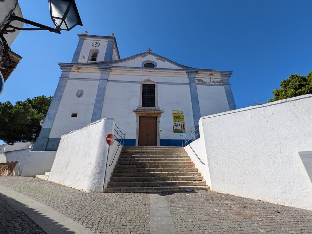 An ancient church mostly white in colour with blue stonework highlights seen a against a blue sky 