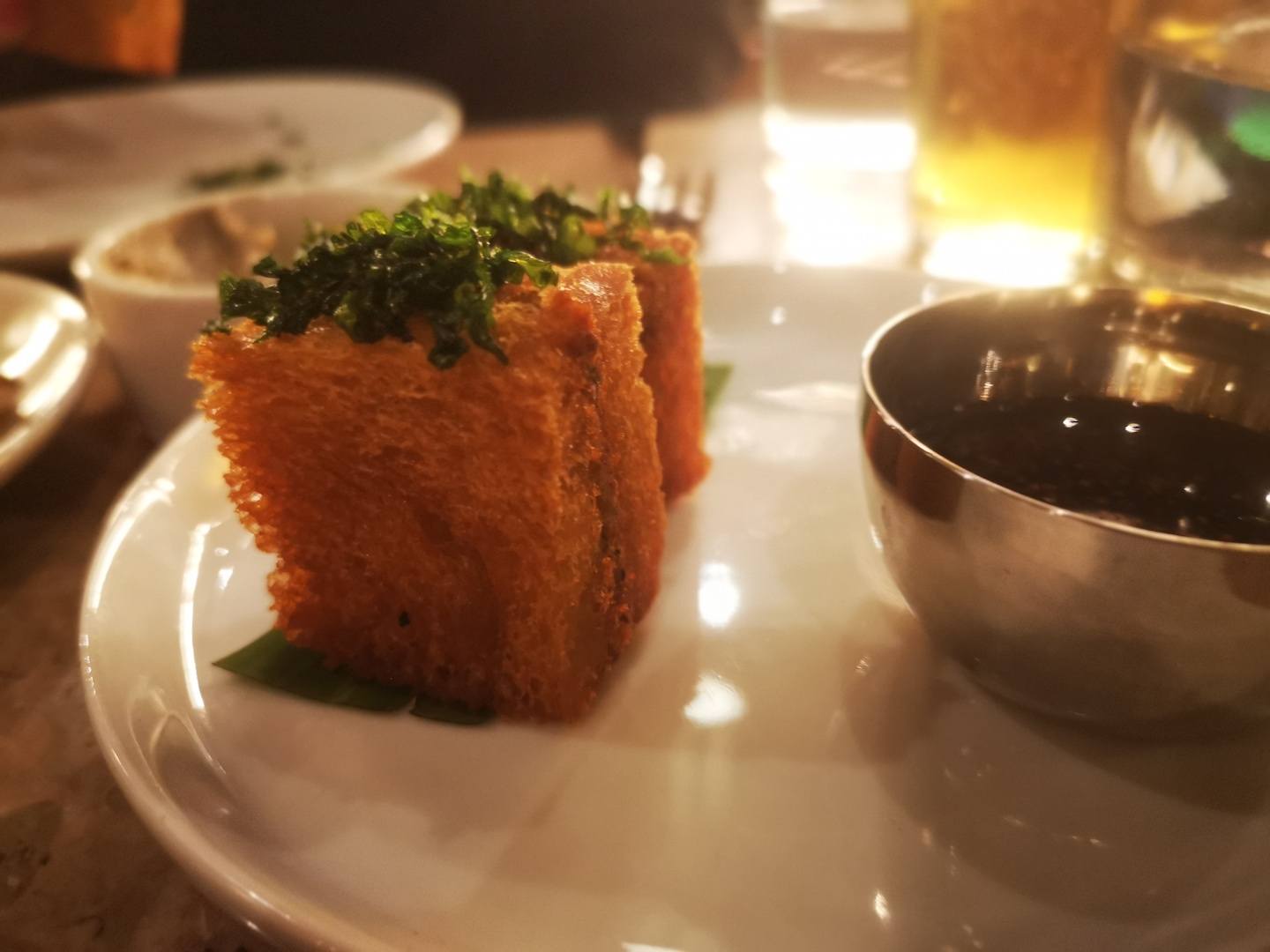 Two cube shaped croquettes on a white plate on a restaurant table.