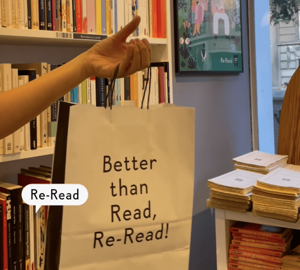 A hand hold a bag in a bookshop with bookshelves visible in the background.