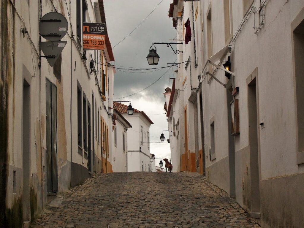 A narrow Street Between Concrete Houses in Evora, Portugal.
