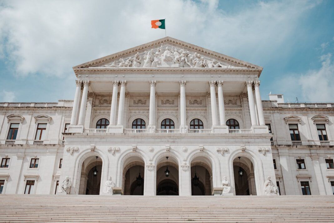 A large, white imposing official building with the Portuguese flag flying at the top of the building.