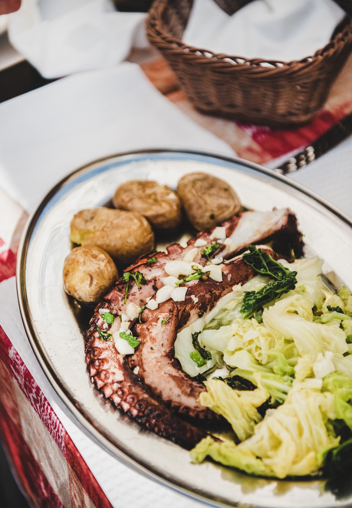 Traditional seafood lunch or dinner in local Lisbon restaurant. Grilled octopus with boiled potatoes and cabbage served on table, selective focus, close-up.