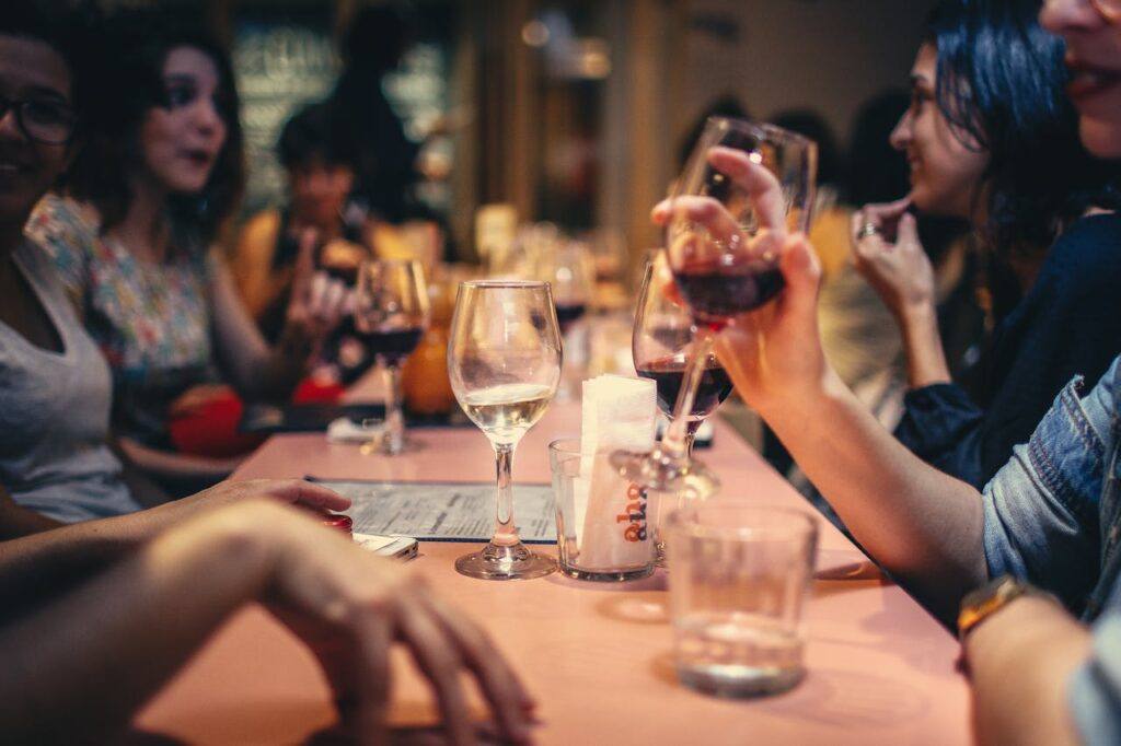 People drinking wine and talking over a dining roo table