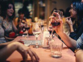 People drinking wine and talking over a dining roo table