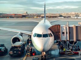 Airplane at airport with passengers boarding and crew.