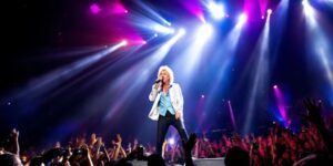 Rod Stewart performing live with colorful stage lights.