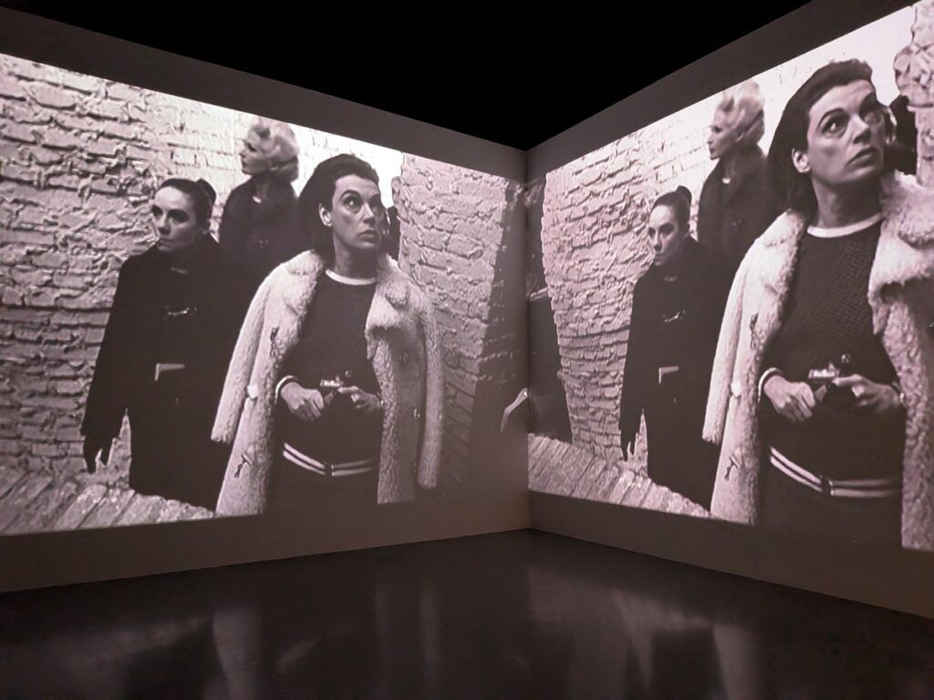 A photo of two, identical stills from a black and white film where a woman stands in front of two men