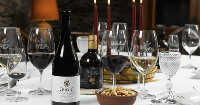 Bottles of Quinta do wine on a table with some nut snacks and glasses