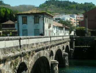 A bridge across a river, with a house and hill in in the background, in Arcos de Valdevez, Portugal.