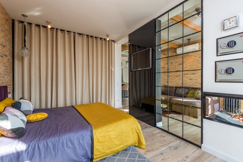 A studio apartment bedroom with a bed and mirroed wardrobe visible.