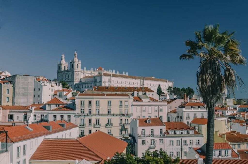 Lisbon Cathedral seen from below against a blue sky and houses around it