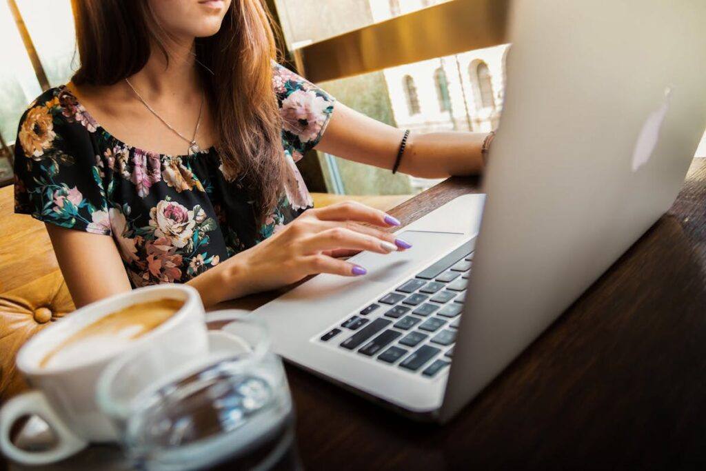 A woman sits in front of a laptop with a coffee up on her desk