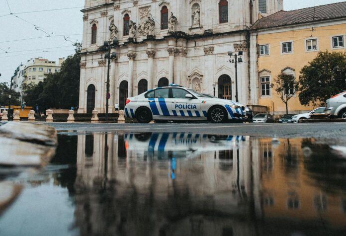 A Portuguese police car parked in a public square in front of buildings