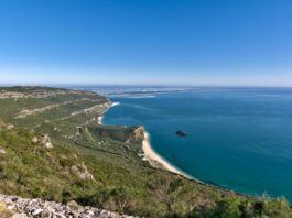 The Arrabida national park coast in Portugal, with sea and coastline visible under a deep blue sky.