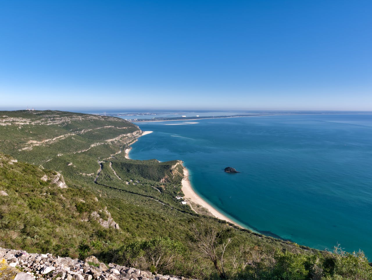 The Arrabida national park coast in Portugal, with sea and coastline visible under a deep blue sky.