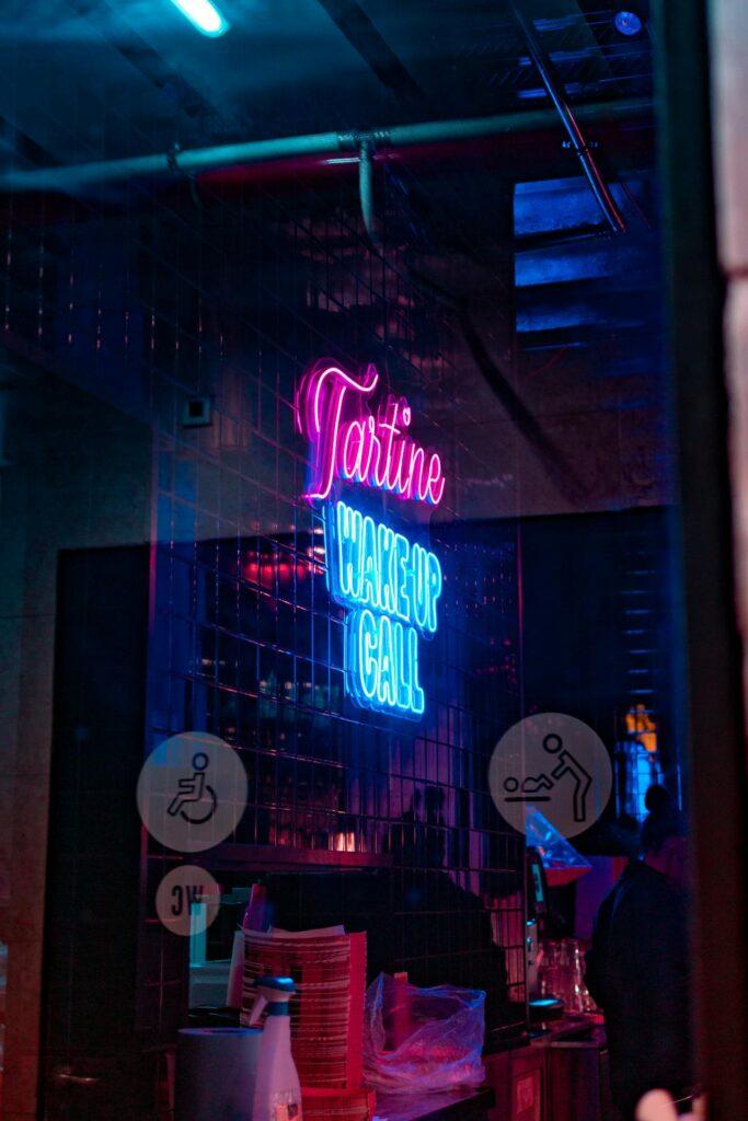 A bar in Lisbon with a neon signn sign saying wake-up call.