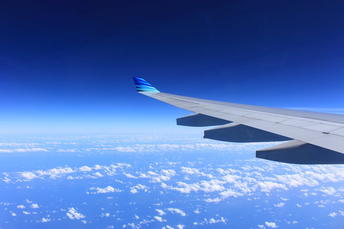 An aircraft wing seen against the sky with white clouds.