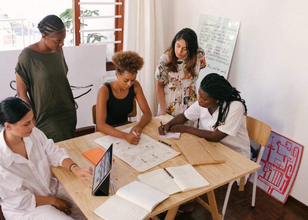 A number of women in a meeting room seated and standing at a table