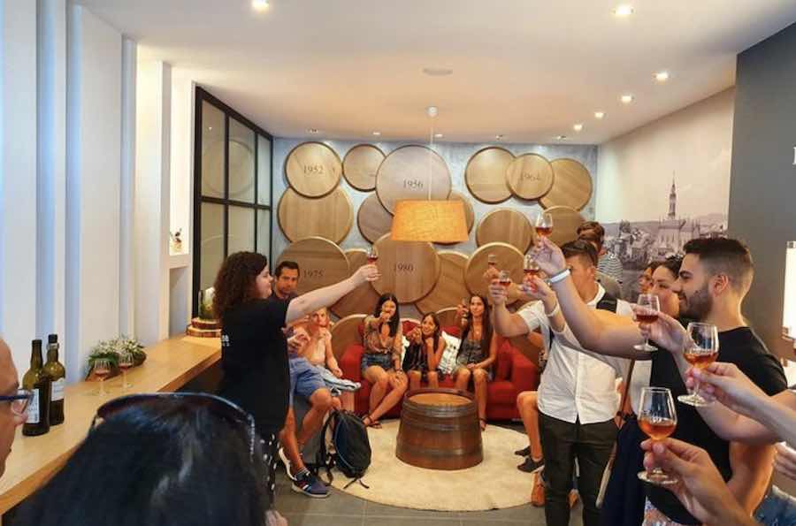 A group of people celebrate with glasses of wine in a room at a vineyard.