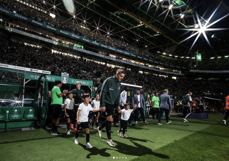 Viktor Gyokeres leads two children on to the pitch at a Sporting Lisbon match.