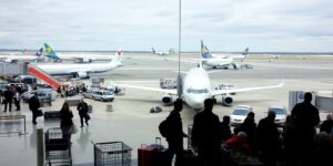 Busy airport with grounded planes and waiting passengers.