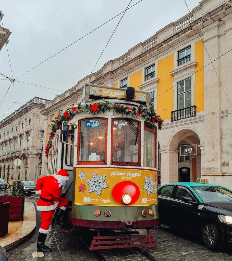 A person in a Santa Claus costume boards a Lisbon tram, that carries Christmas decorations