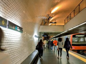 Back View of People Walking and a Blurred Train in an Underground Station