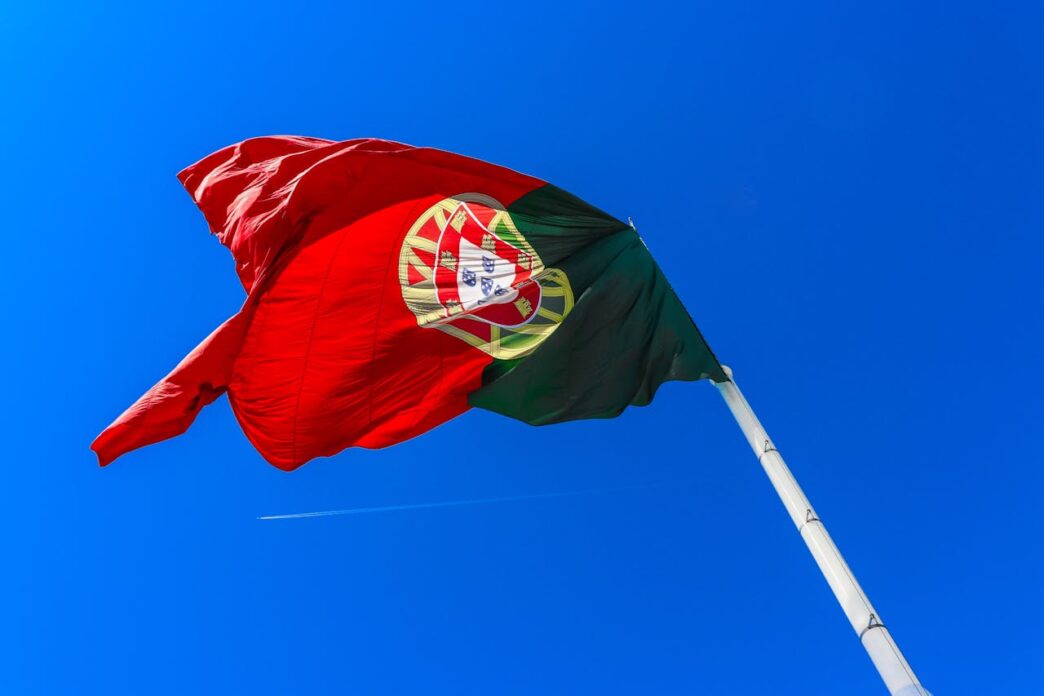 A Portuguese flag seen blowing against a blue sky