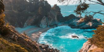 body of water near trees and mountain cliff during daytime